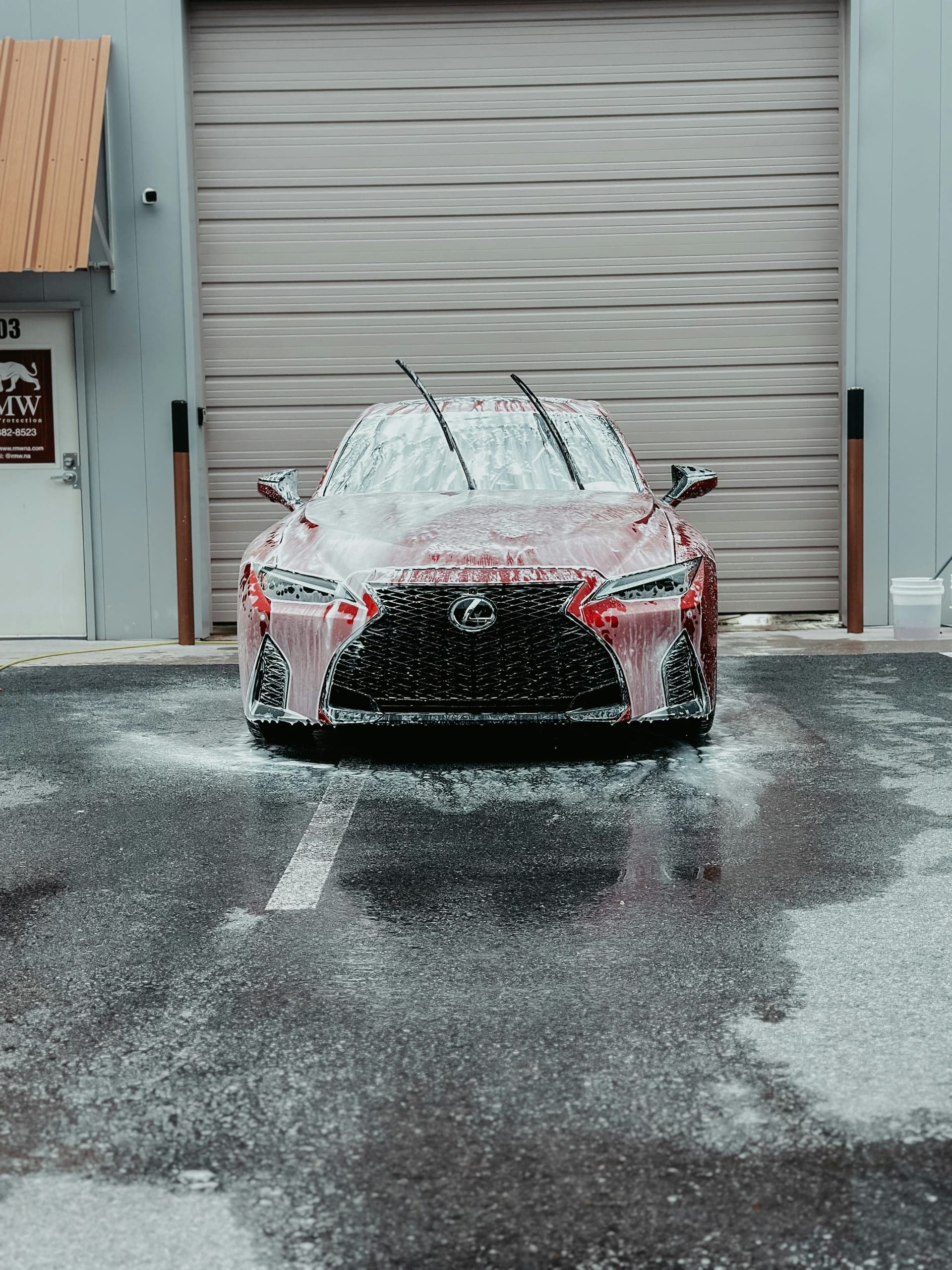Red Lexus sedan covered in foam during a foam-bath wash