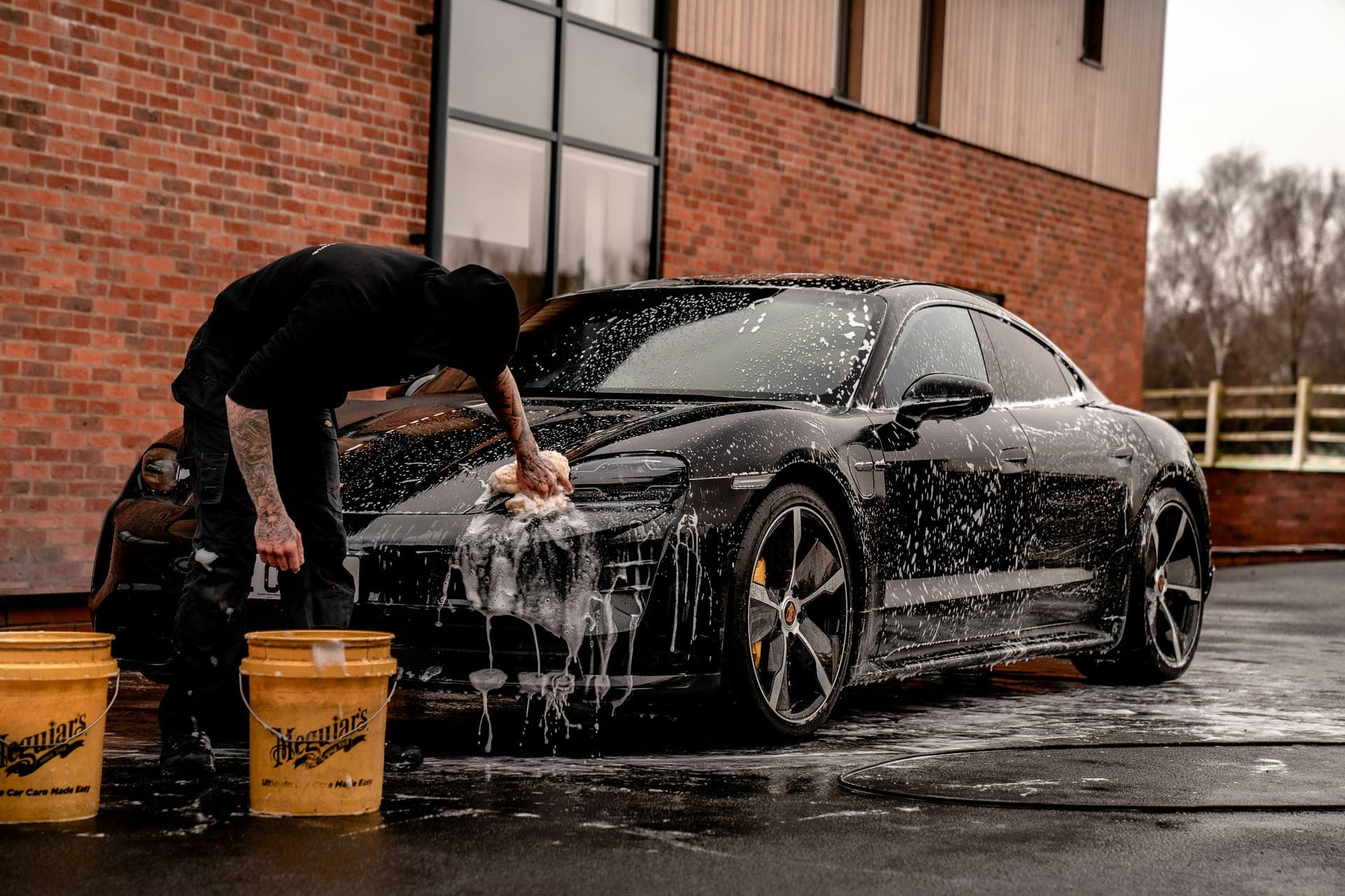 Black Label Detailing detailer hand-washing a black Porsche